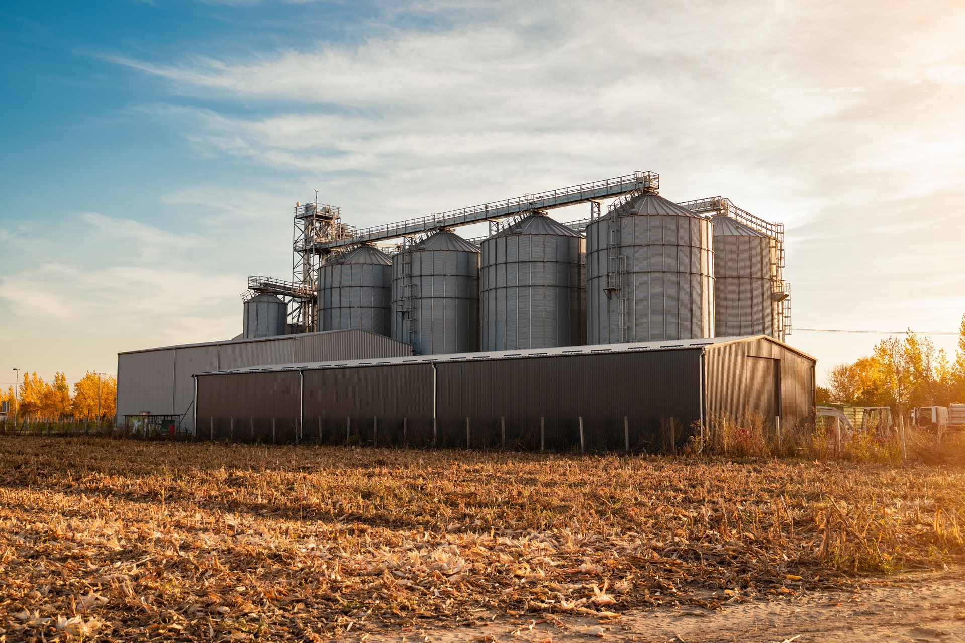 Farm silos and barns at sunset reflecting seasonal farm loan planning for operations
