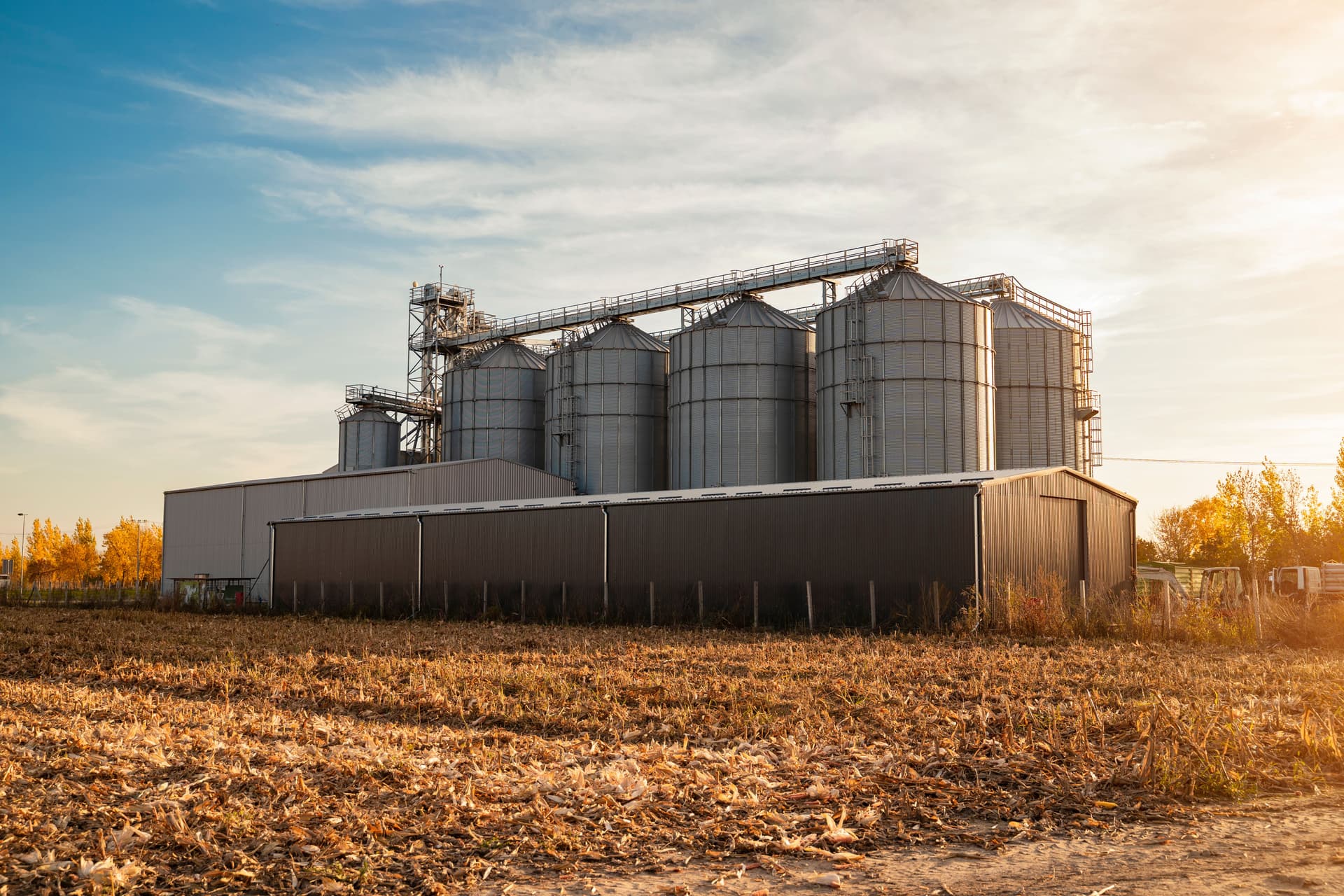 Farm silos and barns at sunset reflecting seasonal farm loan planning for operations