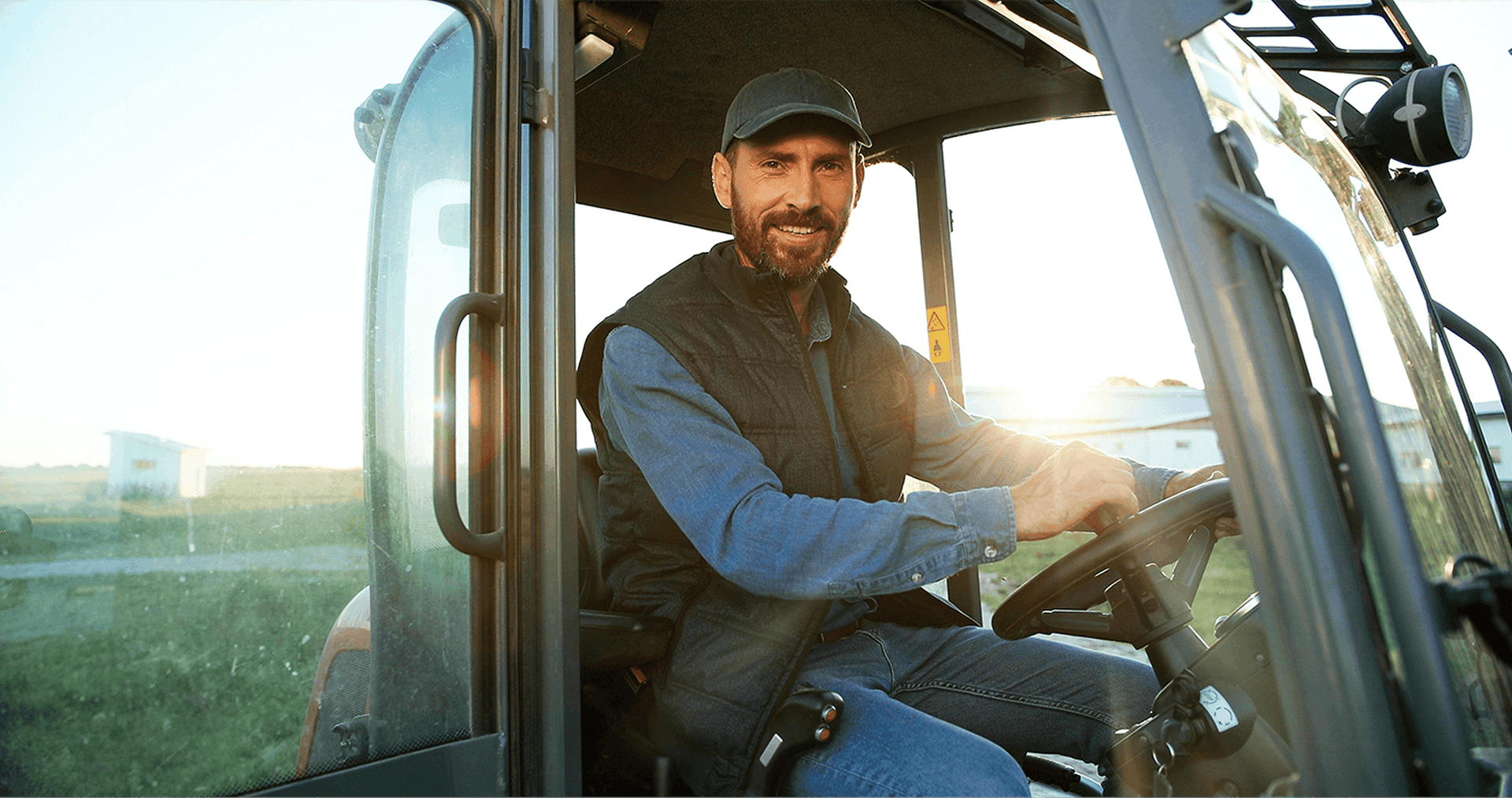Farmer smiling sitting inside a tractor cab after Loan support from National Ag